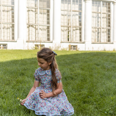 girl sitting on a grass in a dress with ruffles and white lace liberty print