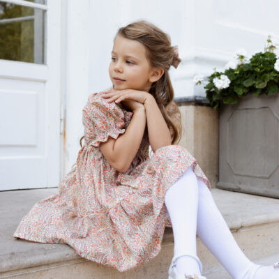 girl sitting on stairs in orange dress with short bubble sleeves and shirred bodice