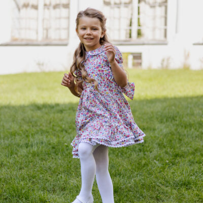 girl twirling in a dress for winter with short bubble sleeves and collar with lace