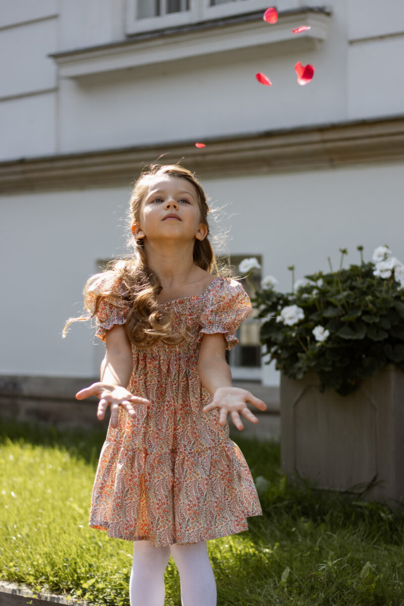 girl throwing petals in orange dress with short bubble sleeves for autumn