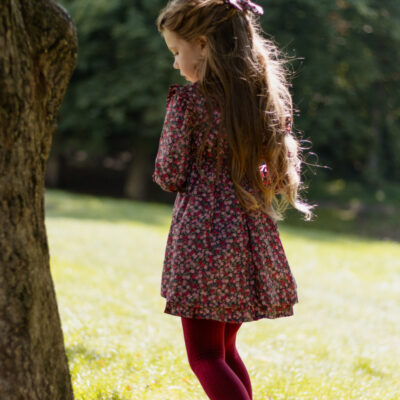 girl next to a tree in burgundy dress with long sleeves
