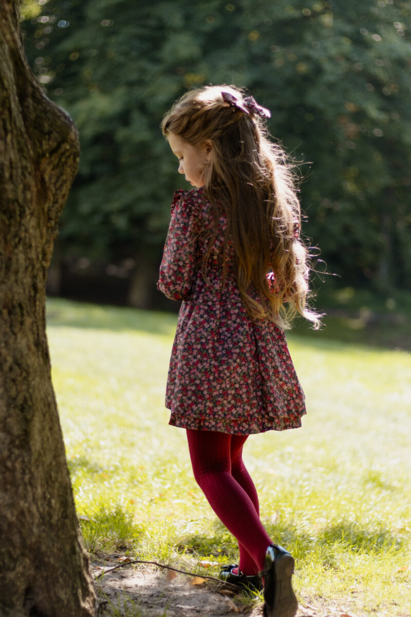 girl next to a tree in burgundy dress with long sleeves