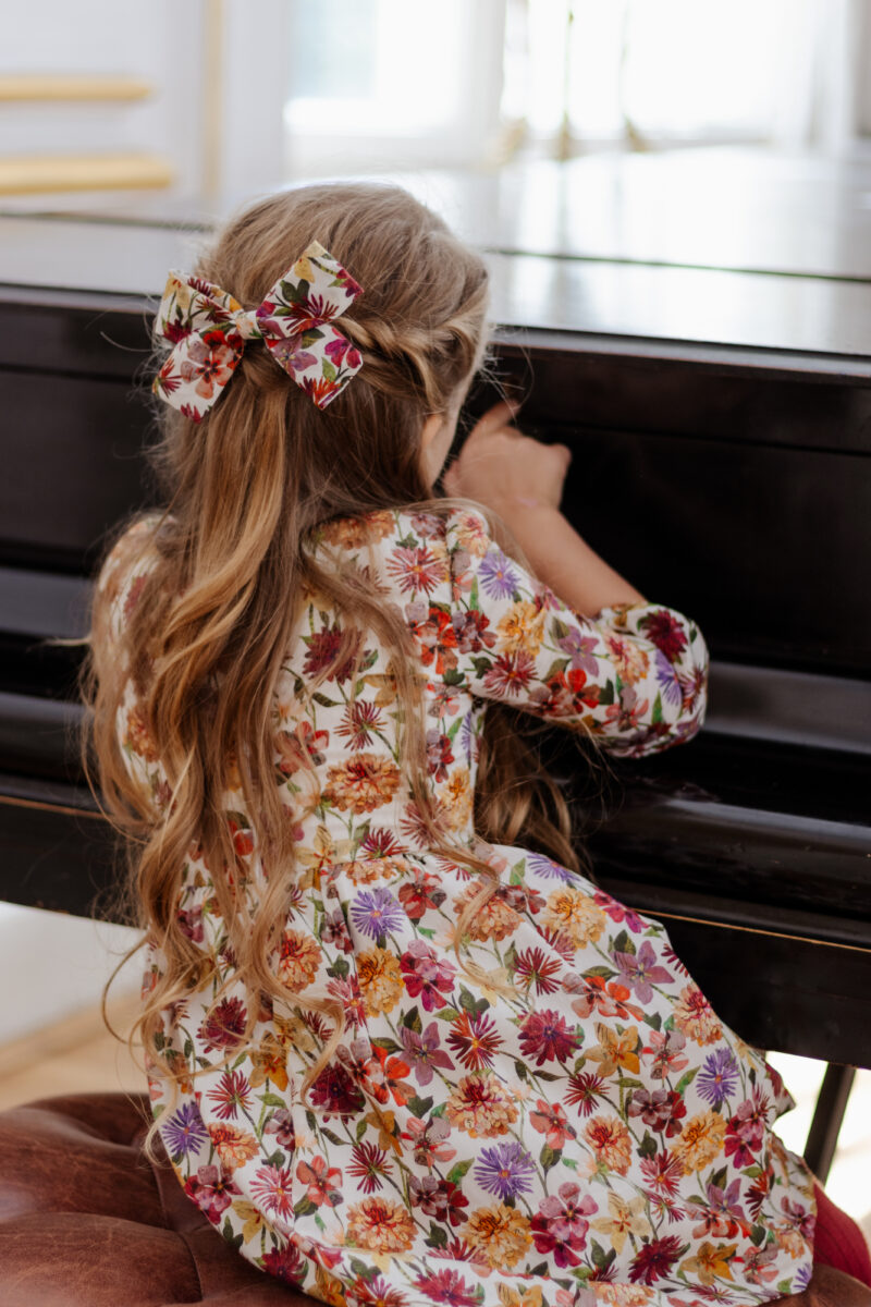 girl in a dress for fall sitting near piano