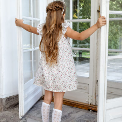 girl closing doors wearing white dress for winter with white socks