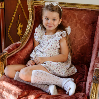 girl sitting on a chair in white dress and headband and white socks