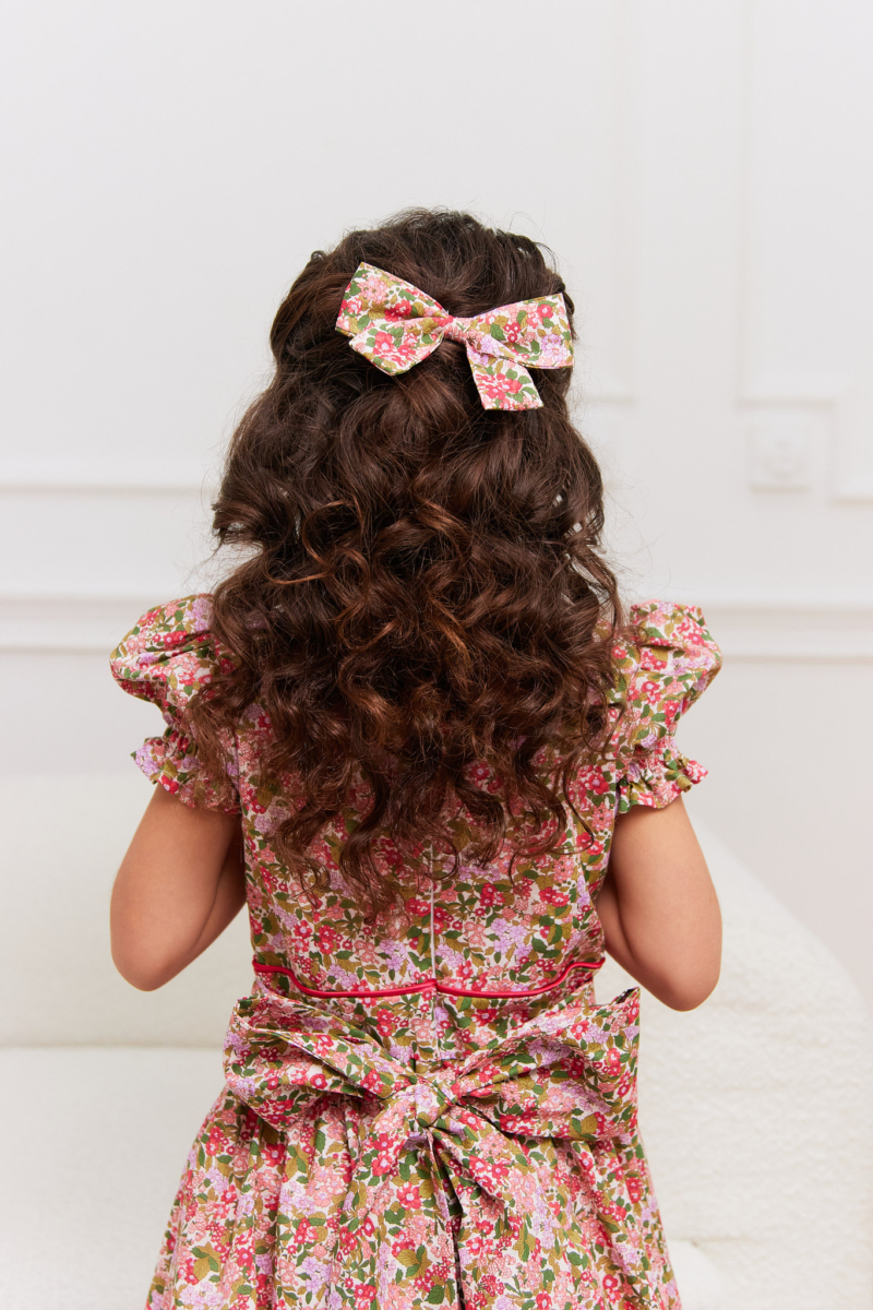 girl wearing hair bow in pretty red and pink flowers tana lawn cotton
