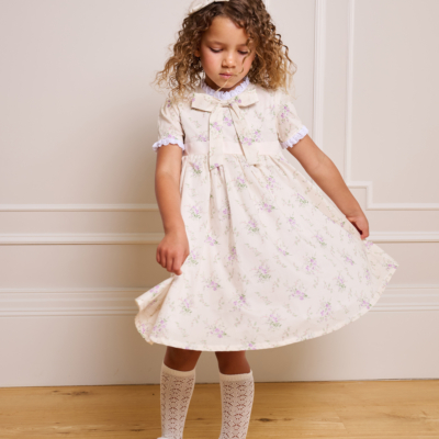 girl spinning in cream dress with bow underneath neckline and white ruffles