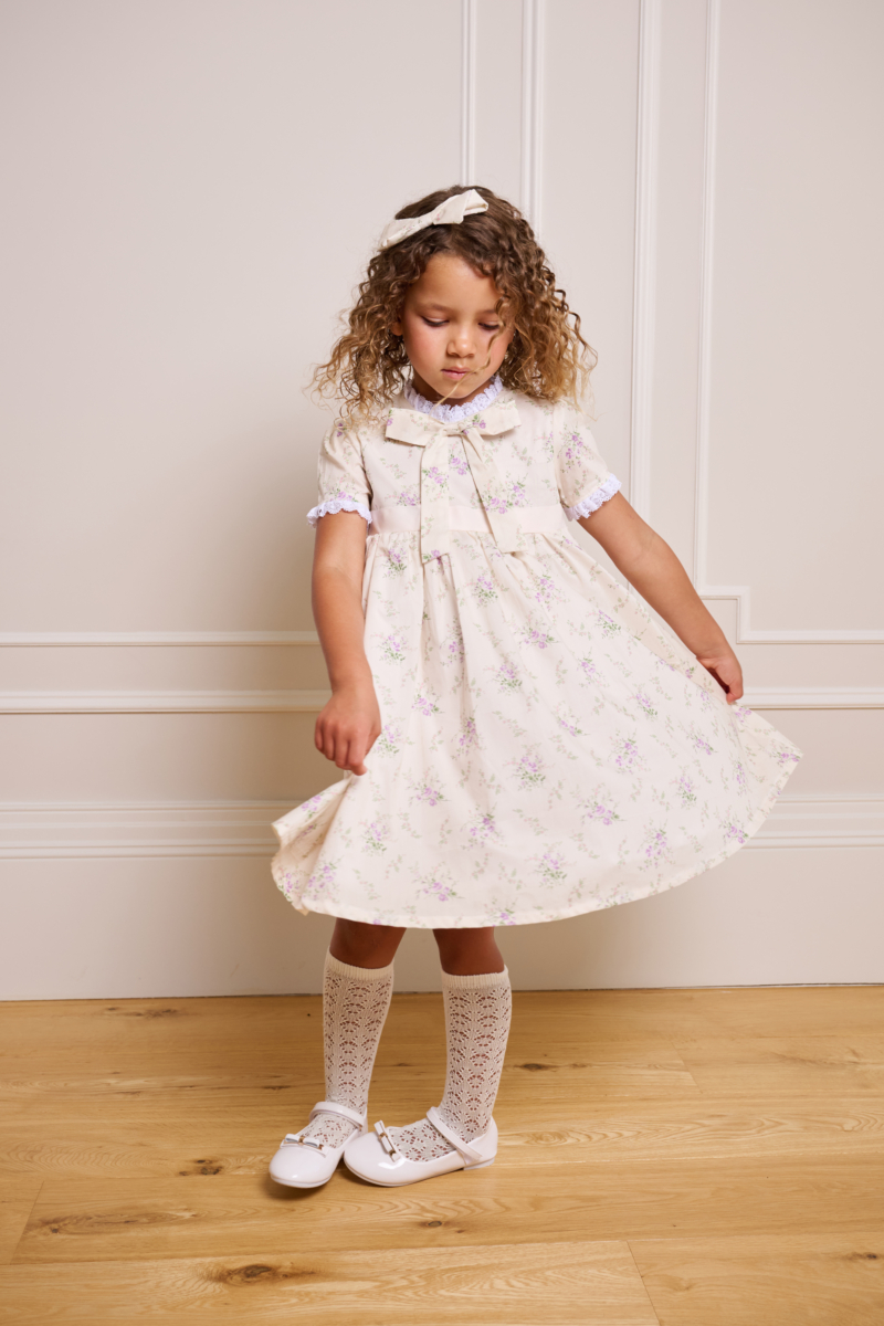 girl spinning in cream dress with bow underneath neckline and white ruffles