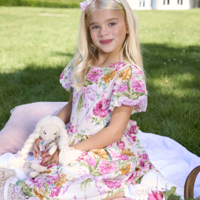 girl sitting on picnic with her doll in floral dress bridgerton inspired