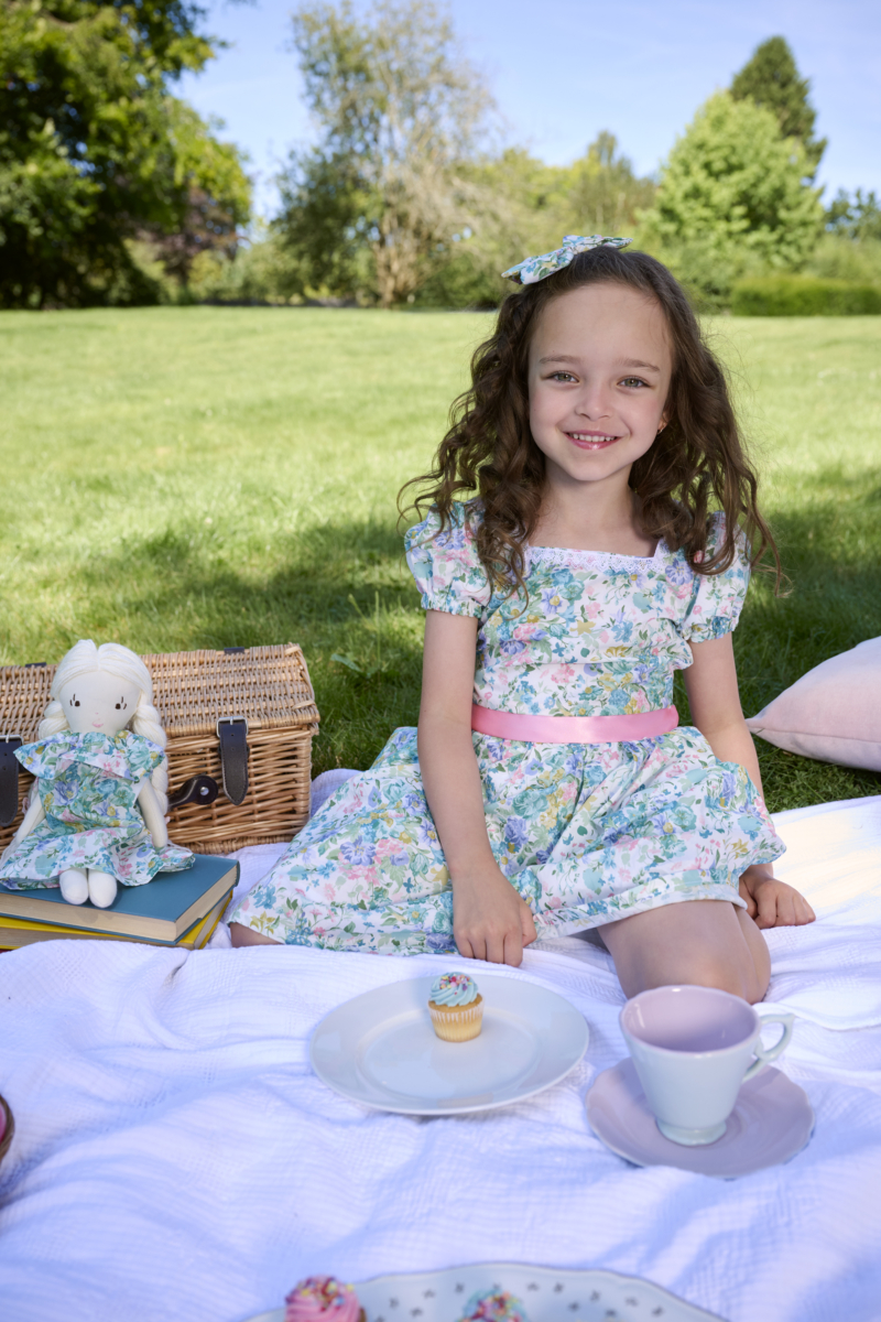 girl sitting on picnic wearing green floral dress bridgerton inspired